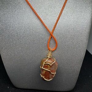 Elegant wire wrapped gemstone pendant necklace with an orange cord.